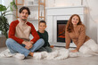 © Pixel-Shot - Happy family sitting near fireplace at home