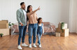 © Prostock-studio - Cheerful amazed Middle Eastern family of three people enjoying moving in new apartment, excited lady pointing finger, satisfied customers relocating into new apartment. Mortgage, renovation
