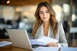 © Milana - Professional Woman in Modern Office Working on Documents with Laptop and Papers