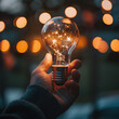 © Malik - light bulb in hand Businessman holding light bulb connected with network concept for idea innovation and inspiration