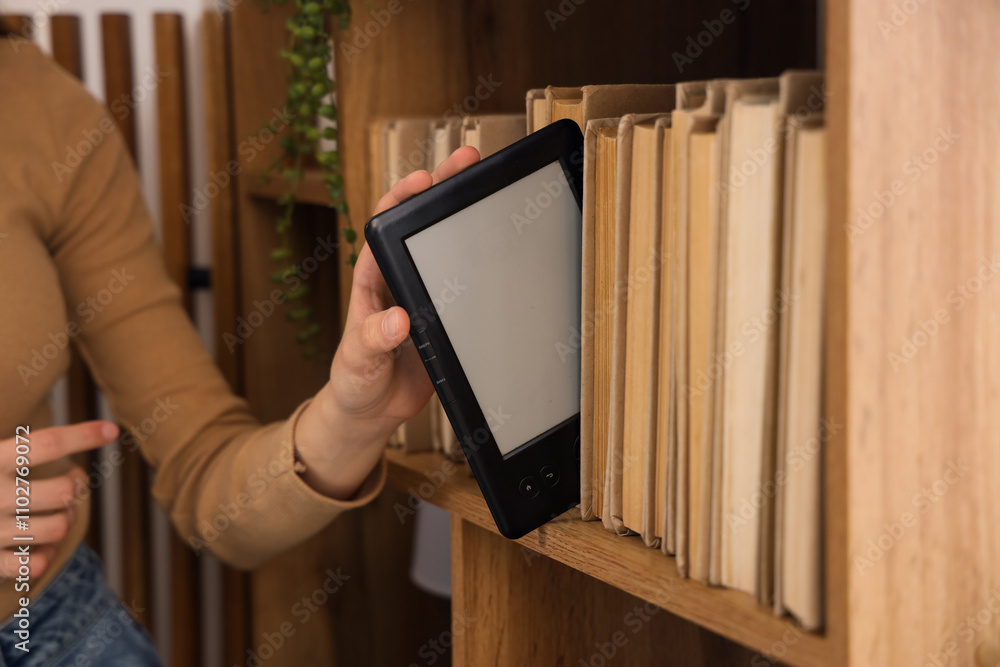Young girl putting e-reader on book shelf