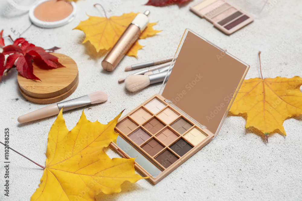 Composition with decorative cosmetic and autumn leaves on light background