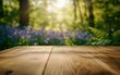 © Pixels  - Ground level angle view close up, surface of light birchwood table, with a floral-inspired forest glade background, blurred bluebells and ferns, copy space, ad promo template, enchanting floral tones