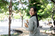 © bongkarn - A charming, happy Asian female college student walks along the footpath on campus on a bright day.