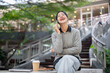 © bongkarn - A cheerful Asian woman sits outdoors, laughing and enjoying a fun conversation on the phone.