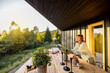 © rh2010 - A woman enjoys the calm of the early morning on her wooden deck, surrounded by nature. The sunlight casts a warm glow on the rustic setting, creating a peaceful and serene atmosphere