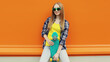 © rohappy - Summer portrait of happy cheerful stylish young woman with skateboard posing on orange background