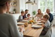 © natakot - A family is sitting together around a kitchen table, enjoying a meal and conversation in a bright, cozy setting. The natural light and relaxed atmosphere create a happy and bonding family moment.