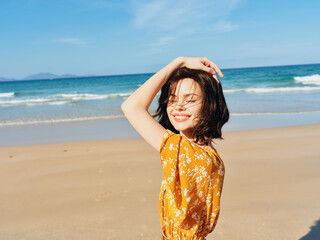 Poster - Woman in yellow dress standing on beach with hands on head in contemplation and appreciation of beauty of nature