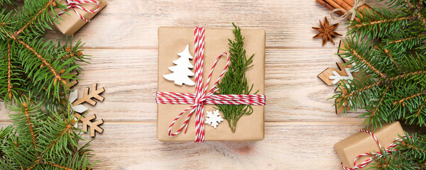 Wall Mural - Christmas background with fir tree and gift box on wooden table. Top view with copy space for your design