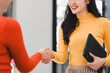 © kenchiro168 - woman in yellow sweater shakes hands with another person, showcasing professional interaction. setting reflects modern office environment, emphasizing collaboration and positivity