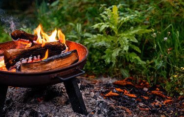 a fire burns at night in a barbecue in the forest.