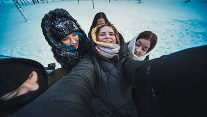 Happy students in cozy winter attire capturing a group selfie in a snowy forest