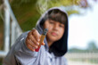 © Aoy_Charin - Close-up of hand holding out electronic cigarette, blurred background of a teenage boy wearing a gray hoodie over his head.