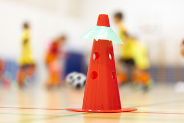 Wall Mural - Futsal Training Cone on Wooden Sports Pitch.. Kids Kicking Futsal Balls in Blurred Background. Indoor Soccer Class For Shcool Kids