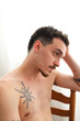 © ADDICTIVE STOCK - Thoughtful young man with tattoos sitting on a wooden chair