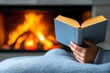 © Thanyarat - A reader enjoying a book by a crackling fireplace, wrapped in a warm blanket on a cold evening