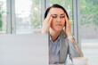 © okrasiuk - Stressed businesswoman working on laptop in modern office. Feeling tired. Frustrated, Overwhelmed executive female. Suffering from headache, exhausted worker sitting with closed eyes, relieving pain