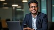© Lakkhana - Smiling Indian or Hispanic CEO, elegant office interior, smartphone in hand, laptop open, confident and professional demeanor