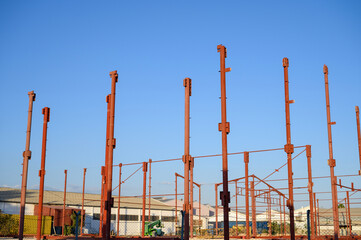 The red metal Structure of a large Industrial Building in the Construction Site 
