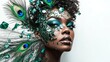 © DZMITRY - An eye-catching portrait of a woman with green and blue makeup, peacock feathers, and fragments of glass, displayed on a white background.
