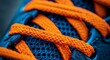 © VIK - Macro photograph of a sneaker with orange laces and detailed stitching.
