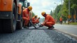 © Kristina - Asphalt road repair work by workers in orange uniforms