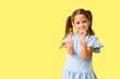 © Pixel-Shot - Happy little girl showing thumbs-up on yellow background