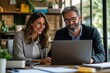 © Pete - Business partners happily work on laptop at office desk reviewing financial project. Team collaborates on computer. Professional executives work together. Modern office environment. Business people
