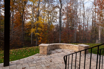 Wall Mural - A serene backyard featuring a curved stone patio surrounded by vibrant autumn foliage, creating a peaceful outdoor space ideal for relaxation and nature appreciation.