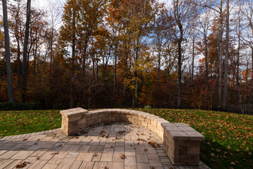 Wall Mural - A serene backyard featuring a curved stone patio surrounded by vibrant autumn foliage, creating a peaceful outdoor space ideal for relaxation and nature appreciation.