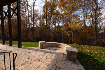 Wall Mural - A serene backyard featuring a curved stone patio surrounded by vibrant autumn foliage, creating a peaceful outdoor space ideal for relaxation and nature appreciation.