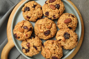 Delicious oatmeal cookies with raisins and nuts on grey table, top view