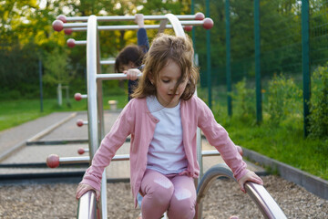 little girl with long hair climbing on playground in summer. healthy active mischievous child concep