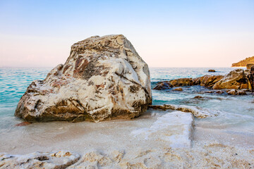 Wall Mural - A large rock sits on a beach near the ocean