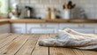 © Lasvu - Dishrag on wood table with blurred kitchen counter backdrop.