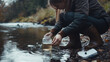 © Keitma - Young woman checking water quality as part of an environmental survey, standing at the edge of a river and collecting a sample in a jar. She wears waterproof boots