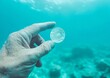 © Ryzhkov - Exploring Ocean Depths Hand Holding a Transparent Object Amid Blue Waters