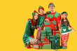 © Pixel-Shot - Happy family in elf's costumes with gift boxes on yellow background