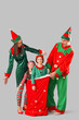 © Pixel-Shot - Happy family in elf's costumes with Santa bag on grey background