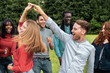 © Lomb - Young diverse friends dancing together, spinning and twirling with authentic joy in summer park
