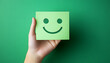 © john - Hand holding green paper cut happy smile face on green background , positive thinking
