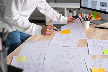 Wall Mural - ux ui designer working on wireframes for a website and mobile app prototype, surrounded by sketches 