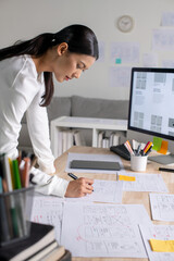 Wall Mural - ux ui designer working on wireframes for a website and mobile app prototype, surrounded by sketches 