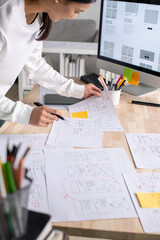 Wall Mural - ux ui designer working on wireframes for a website and mobile app prototype, surrounded by sketches 
