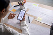 © amenic181 - UX UI designer testing prototype on a phone, discussing and brainstorming on wireframes for a website and mobile app prototype, in the concept of website and mobile application design concept.