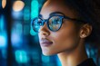 © quietmind_art - African female adult analyzing data reflections on glasses in a tech environment.