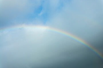 real photo of a rainbow in the sky with clouds and blue sky