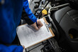 © zphoto83 - Mechanic reviewing inspection checklist during vehicle maintenance in a garage