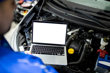 Wall Mural - Mechanic using blank screen laptop to diagnose car engine issues in auto repair shop during daytime